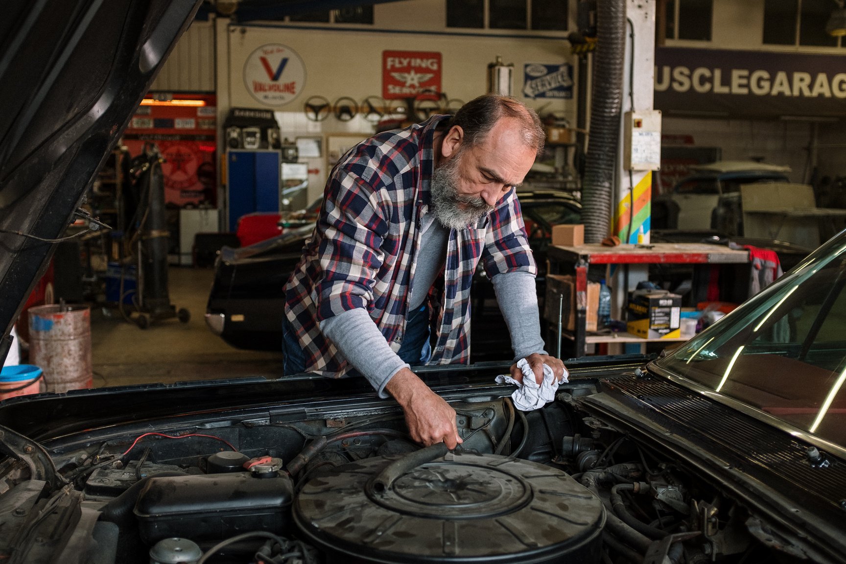 Man in Red White and Black Plaid Dress Shirt Holding Black Car